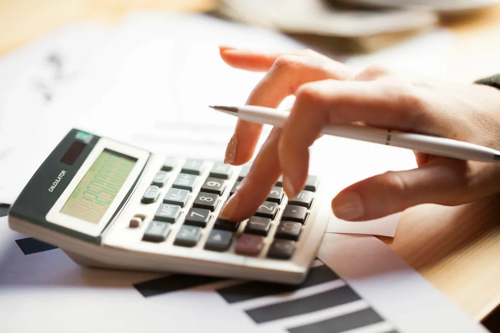 hand holding a white pen and inputting on a calculator